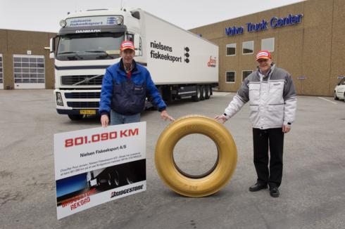  Bruno Hansen, regionalny przedstawiciel handlowy Bridgestone w towarzystwie Poula Jensena, kierowcy Nielsens Fiskeeksport, z dyplomem i jedną z jego używanych opon M729, która, specjalnie na tę okazję, została pomalowana na złoto