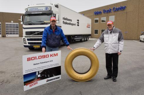 Bruno Hansen, regionalny przedstawiciel handlowy Bridgestone w towarzystwie Poula Jensena, kierowcy Nielsens Fiskeeksport, z dyplomem i jedną z jego używanych opon M729, która, specjalnie na tę okazję, została pomalowana na złoto